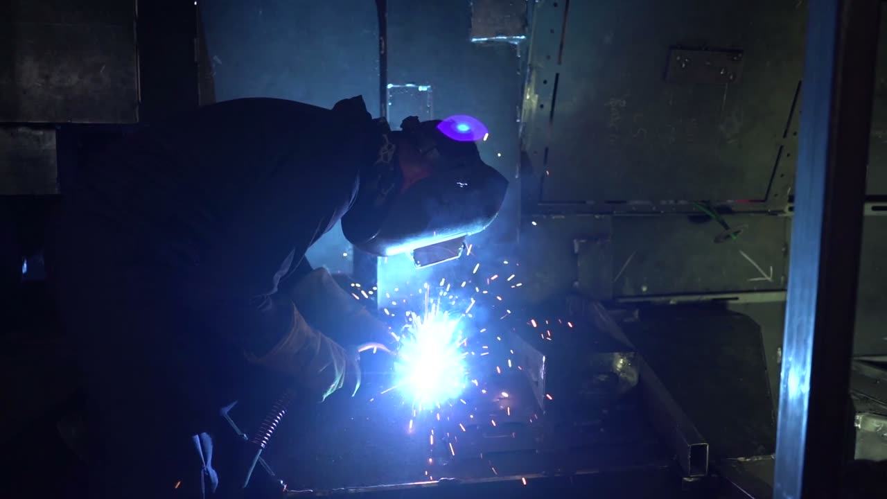 Welder at work on a steel joint, sparks flying